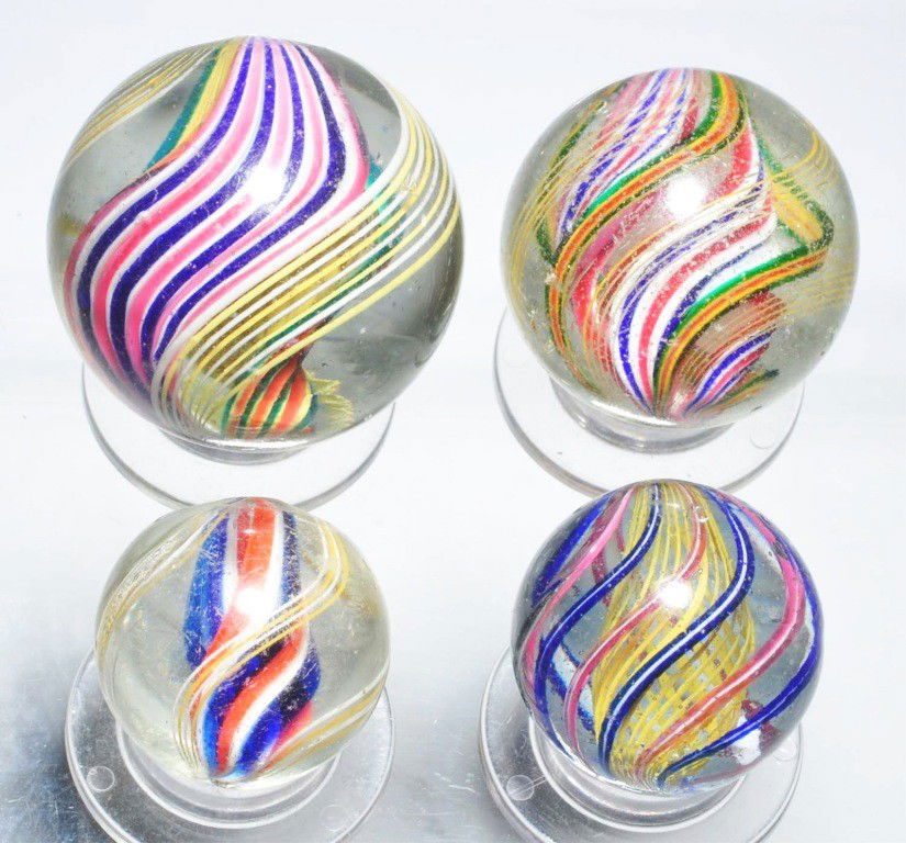 Lot of 4: Swirl Marbles.: Largest is a double ribbon red/white/blue with outer alternating bands of white and yellow latticino. Smallest is a divided core of red/white/blue with outer bands of alternating white and yellow latt