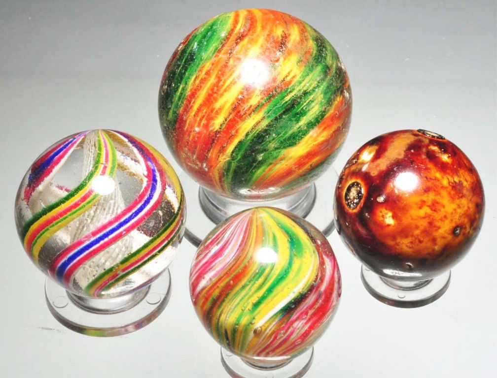 Lot of 4: Assorted Marbles.: Includes one white latticino swirl marble with outer alternating bands of red, white, blue, green, yellow, and pink and one polished four-lobed onionskin marble with opposing panels of yellow and gree