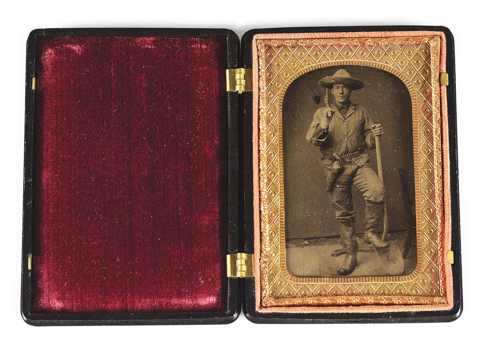 CASED MERWIN & HULBERT ARMED MINER TINTYPE IMAGE.: 1870s - 1880s rectangular format tintype image of an armed miner holding a pick and shovel. He is wearing a large brimmed western style hat, and on his cartridge belt is a Merwin & Hulbert large frame