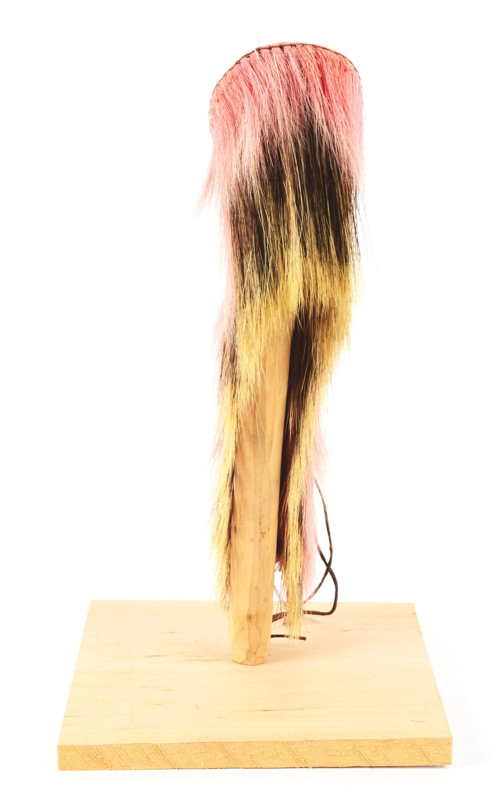 NATIVE AMERICAN HAIR ROACH WITH STAND.: Circa early 20th century Northern Plains hair roach. Roach is orange dyed deer hair surrounding porcupine guard hair over red, orange, and blue wool backing trimmed in quill with long harness leather