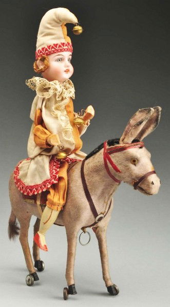 Bisque Head Clown on Donkey Pull Toy.: Bisque head incised "70.195" with glass eyes, open mouth, original mohair wig. Wood torso, wired arms and legs, wood hands and feet, original costume. Seated on a felt-covered donkey with wheels on hi