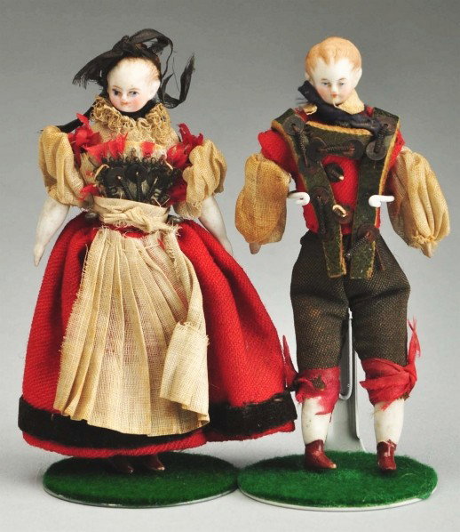 Pair of Parian Doll House Dolls.: Parian shoulder heads with blonde molded hair, individual brush strokes around faces, dainty faces with finely detailed painted features, cloth bodies, bisque lower arms and leg with painted white sto