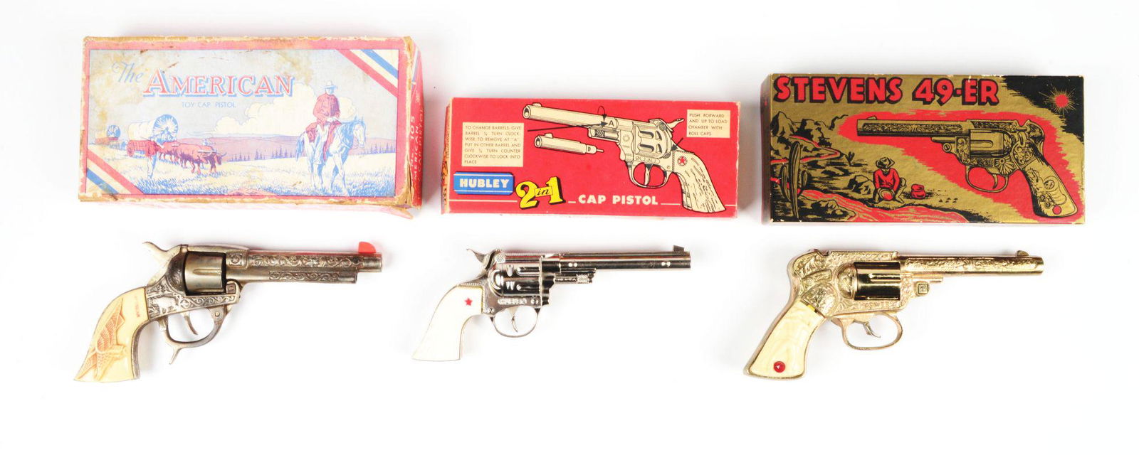 LOT OF 3: 1950'S AMERICAN-MADE CAST IRON CAP PISTOLS.: All in original boxes. Includes Hubley "2 Guns in 1" cap pistol with changing barrels, a Kilgore American cap pistol and the last is a Stevens 49-er. Box to American cap pistol has some staining, edge