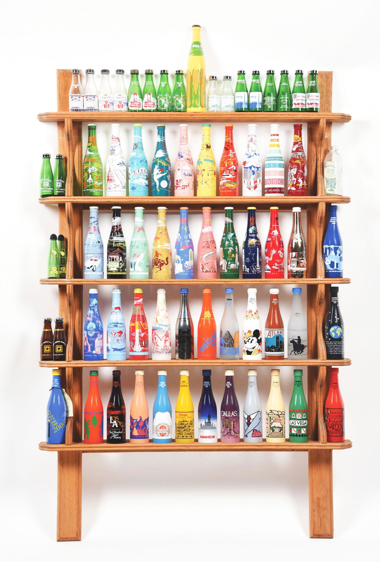 COCA-COLA BOTTLE RACK WITH BOTTLES.: This is a complete set of commemorative bottles issued each year at the "National Soft Drink Association" convention from various cities and states. Inclusive of all years 1950 - 2000, in unused condi