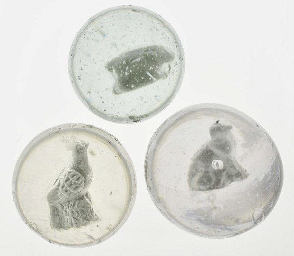 Lot of 3: Sulphide Marbles.: The largest marble is a dog sulphide with well-centered figure. The surface is in great condition but the marble is out of round. The smallest marble is a pig sulphide. Also includes a bird sulphide w