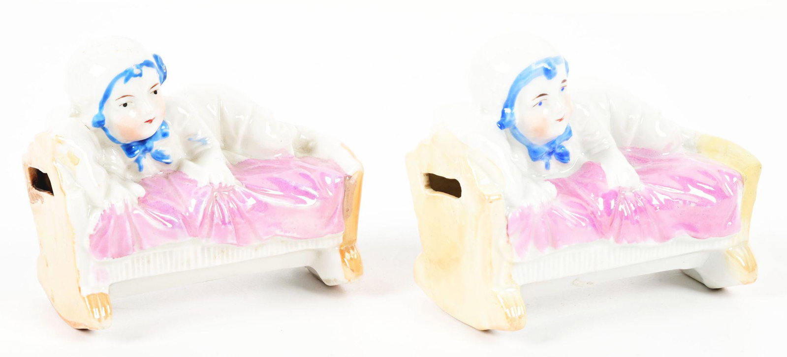 LOT OF 2: CHILD ON CRADLE BANKS.: Both are ceramic. Circa 1910 Condition: (Excellent Plus). Dimensions: Each: 2 - 3/4" x 1 - 3/4" x 2 - 1/2".