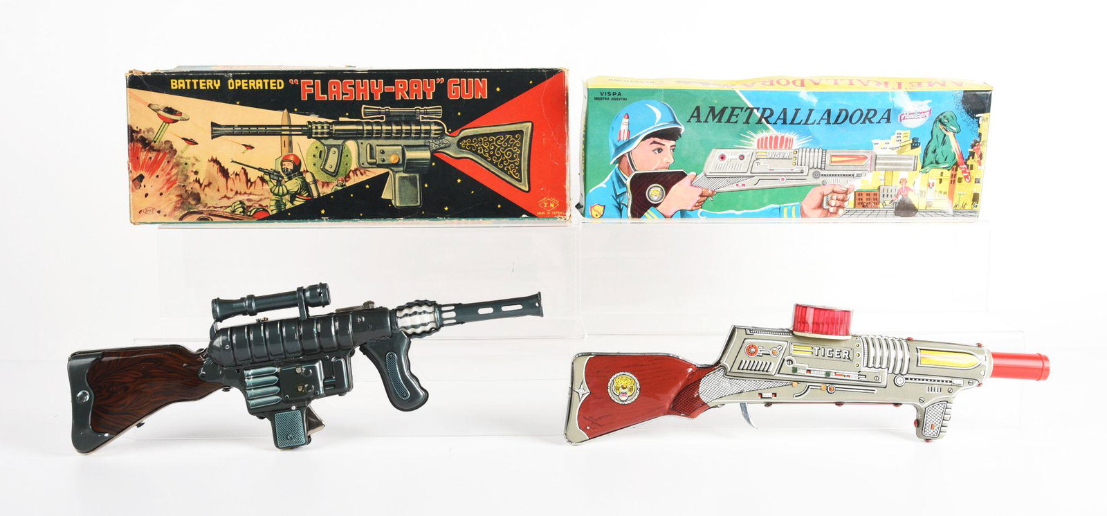 LOT OF 2: FOREIGN MADE TIN LITHO BATTERY OPERATED & FRICTION SPACE RIFLES.: Japanese battery operated Flashy Ray gun by Namora and Tiger gun made in Argentina that is friction. Some creasing to boxes. Condition: (Very Good - Excellent). Dimensions: Largest Box: 19" x 6 - 1/2"