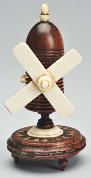 Windmill Figural Tape Measure.: Inlaid wood. The celluloid windmill blades wind the tape. Numbers are worn on the original silk tape. Condition (Excellent). Size 3 - 1/2" T.