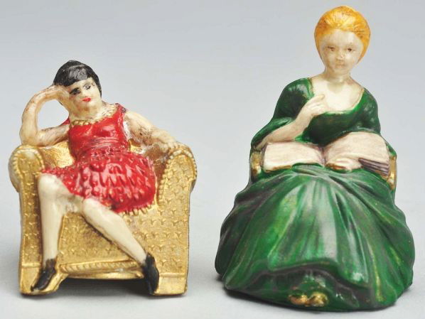 Lot of 2: Ladies Sitting in Chairs Tape Measures.: German. Celluloid. Spring tapes. The tape for the lady in red is short and sluggish. Condition (Excellent). Size Largest: 2" T.