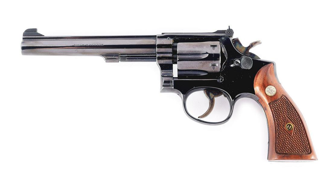 (C) SMITH & WESSON MODEL 17 REVOLVER.: This gun sports a 6" matted ribbed barrel with a post front sight and factory adjustable rear sight. 6-shot fluted swing out cylinder. 3-screw frame with large diamond checkered wood grip panels. COND