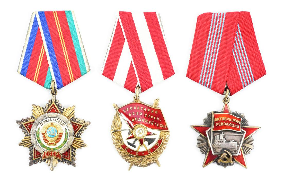 LOT OF 3: SOVIET ORDERS OF OCTOBER REVOLUTION, RED BANNER, AND FRIENDSHIP AMONG PEOPLES.: Lot contains a Soviet Order of the October Revolution (serial #26597), an Order of the Red Banner (serial #262874), and an Order of Friendship Among People (serial #14529). CONDITION: Overall excellen