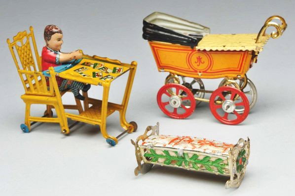 Lot of Tin & Metal Toys.: Description Tin penny toy boy sitting at a play table that extends up into a high chair; tin penny toy doll carriage with hood and blanket (missing baby), white metal cradle with flat baby. Condition 