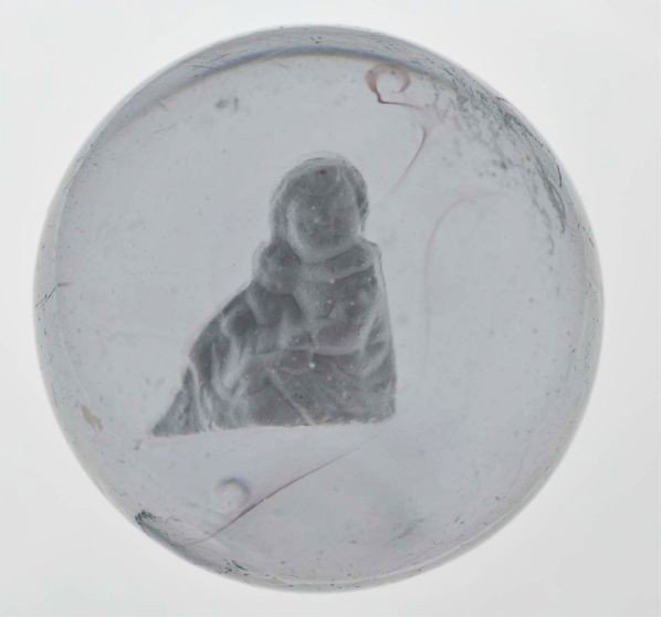 Girl Holding Doll Sulphide Marble.: Description Figure is well-centered. Several fine streaks or swirls of translucent purple glass inside. Photo list: B, C, and D. Condition (9.2). Size 2 - 1/8"" Dia."