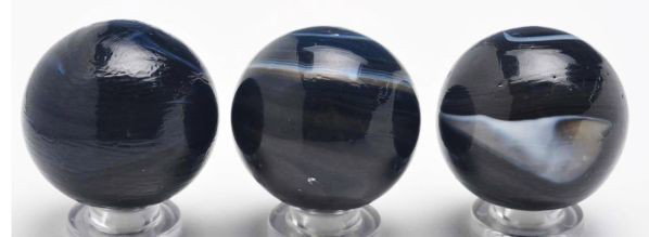 Lot of 3: Single Pontil Navarre Marbles.: Description The smaller marble is a charcoal black opaque with trace of white at the pontil. The larger marble is a charcoal black opaque and has a white ""s"" on top and a white circle above the midd