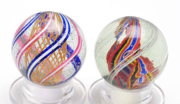 Lot of 2: Swirl Marbles.: Description The smaller marble is a divided core, each of the three ribbons contains stripes of red, yellow, blue, white, and translucent purple. Outer decoration consists of groups of white latticino