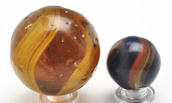 Lot of 2: Banded Transparent Marbles.: Description The smaller marble is a dark amber base with two bands of orange and yellow and one band of yellow, just under the surface. The larger marble is an amber base with broad bands of white on