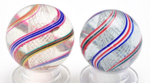 Lot of 2: White Latticino Swirl Marbles.: Description The smaller marble is a white latticino core with two outer bands with red center bordered by white and then blue. Two outer bands have a green center bordered by white and then red. One a