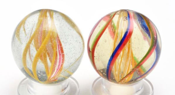 Lot of 2: Swirl Marbles.: Description Includes one bicolor latticino. Core alternates yellow and white threads. Outer decoration of red and green alternating with red and blue. Photo list: C and D. Also includes a three strand