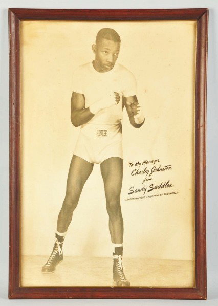 Framed Sandy Saddler Boxing Photograph.: Description Nicely framed. Depicts Sandy in training. Facsimile "To my manager Charlie Johnston from Sandy Saddler Featherweight Champion of the World". Some water staining, appears to have hung in a 