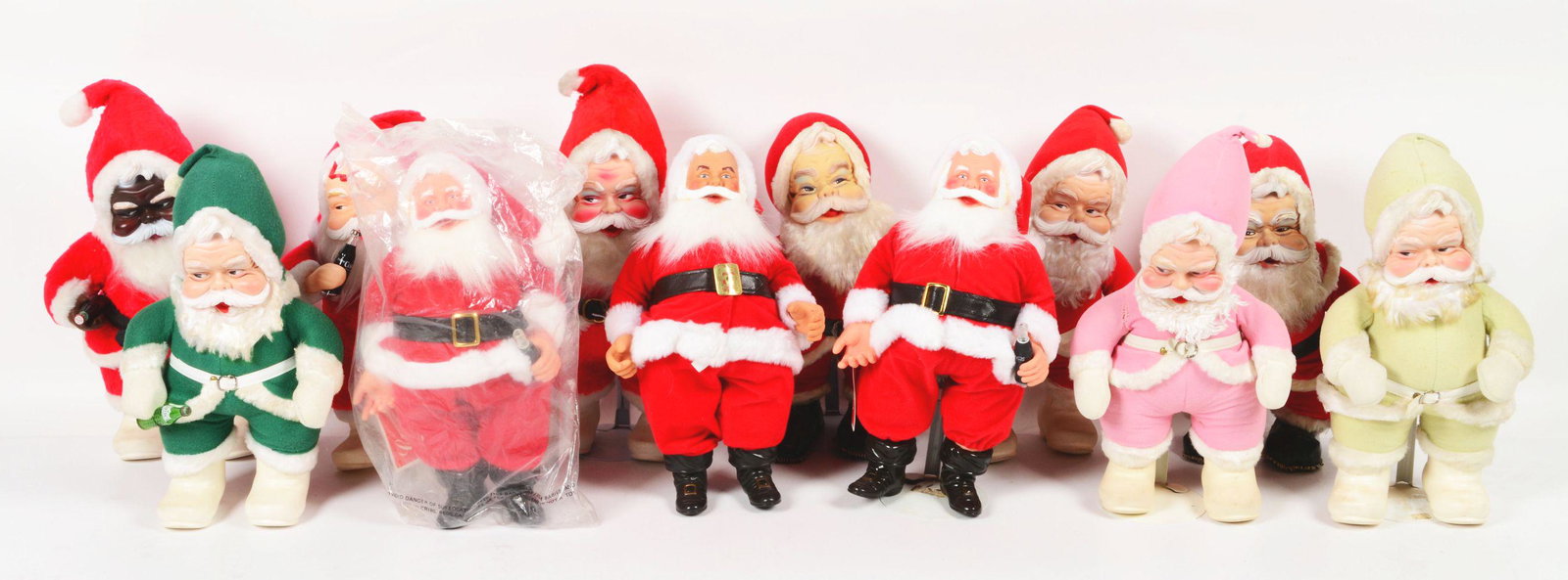 COLLECTION OF TWELVE COCA-COLA SANTAS.: This difficult to find collection includes several Rushton Santa Clauses. Includes a Pink Valentines Santa and a green Sprite Santa. All are in very good condition with minimal discoloration, consiste