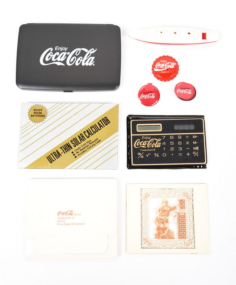LOT OF COCA-COLA ADVERTISING ITEMS.: The Coca-Cola advertising items consist of an early Coca-Cola light-up cap button, two Coca-Cola buttons, a Coca-Cola whistle and an electronic Coca-Cola calculator.Condition:(8.5 - 9.0).Largest: 5" x