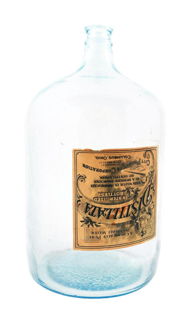 DISTILLATA GALLON GLASS JUG.: Probably from an old water dispenser for an office. One of the first pure waters in sterilized bottles. Still has the old labels attached. A little bit of browning and water damage to it. Overall inta