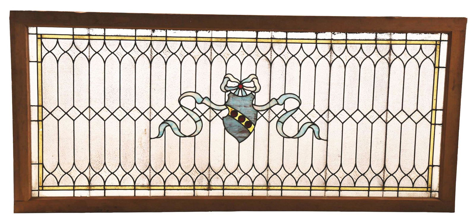 LARGE STAINED GLASS TRANSOM WINDOW.: A beautiful stained glass transom window. The 93 - 1/2" long window in its wooden frame features a background of frosted purple glass in a geometric pattern. There is a blue shield in the center, whic