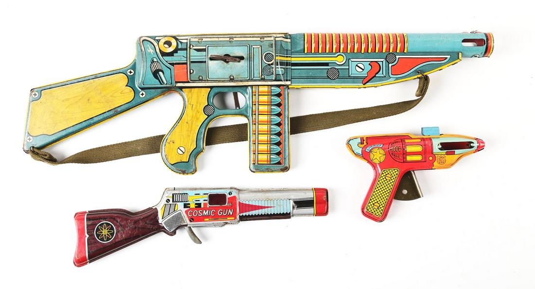 LOT OF 3: VARIOUS JAPANESE & AMERICAN-MADE TIN LITHO GUNS.: One is a unique arm machine gun, one is a Japanese Cosmic Ray Gun and the last one is a Shine Ray Gun. Various conditions. Condition:(Very Good).Largest: 25" x 7 - 1/2" x 2".Dimensions: