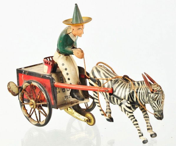 Tin Litho Lehmann Zikra Wind-Up Toy.: Description German. Working. Depicts zebra pulling man in cart. When in operation, man rides up and down. Original ears and legs on zebra. Some pitting and wear to wheels. Condition (Very Good). Size