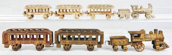 Cast Iron Train Sets.: Description American. Both include a steam-type engine and tender pulling passenger cars. The larger set marked "23 Skiddoo" and "60 Choo-Choo". Some oxidation, wear, and paint touchup to both. Condit