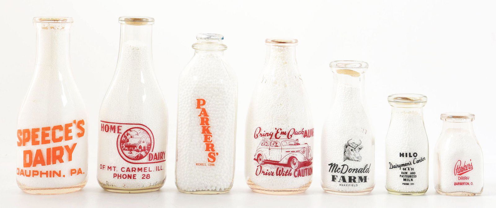 COLLECTION OF 7 VARIOUS MILK JARS.: CONDITION: Excellent graphics and strong colors. Free of breaks or chips. Condition: (9.0+) Dimensions: Largest: 3 - 3/4" x 3 - 3/4" x 9 - 1/2".