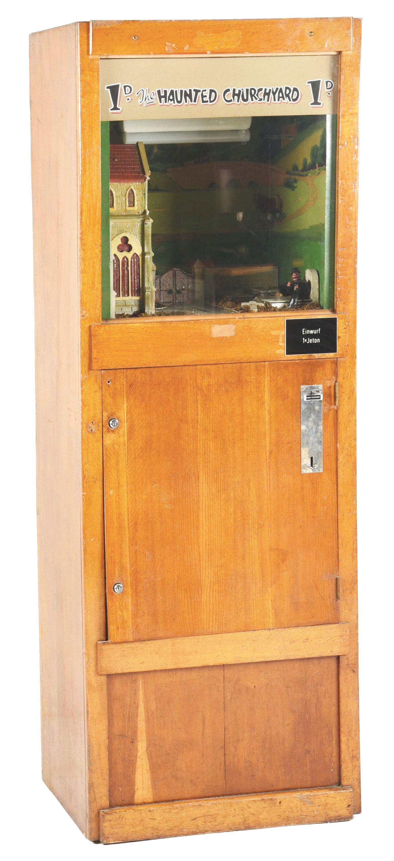 GERMAN "THE HAUNTED CHURCHYARD" WORKING MODEL ARCADE MACHINE.: A wonderful working model arcade machine called the Haunted Graveyard. An old man in the graveyard with his bottle, as the grave opens and a surprise appears. CONDITION: This machine operates on a Ger