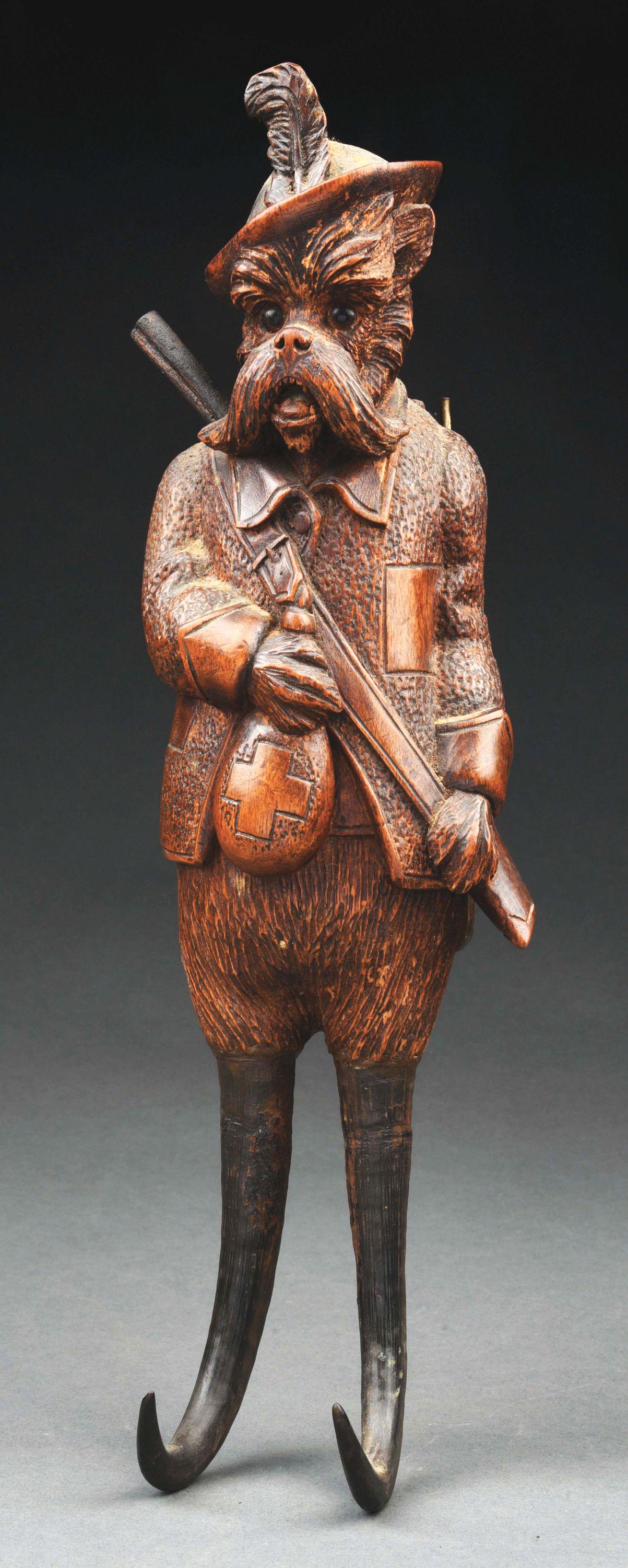 BLACK FOREST CARVED MUSICAL COAT HOOK.: This music box/coat hook is carved in the form of a dog dressed as a hunter holding a flask and a rifle. His legs are made of chamois horn, eyes are glass and the body contains the swiss made music wo
