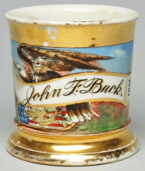 John F. Buck Shaving Mug.: Name "John F. Buck" written across the front. Dated 1913. Nice image of eagle with banner in his talons. "Germany" mark on bottom. Condition (Very Good). Size 3 - 1/2" T.