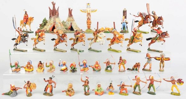 Large Lot of Elastolin Indians.: Includes one composition group with approximately 13 mounted, 56 on foot, teepees, campfires, totem poles, and others. Some cracks and wear throughout. Condition (Good - Very Good). Size Largest: 7 cm