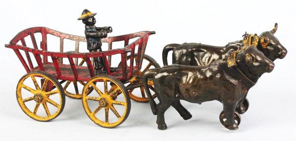 Cast Iron Ox-Drawn Hay Cart Toy.: Includes original African American driver. Cart is drawn by two oxen and has a wired-on cast iron yoke. Some moderate paint loss and wear, especially to yoke and inside of wagon cage. Condition (Very