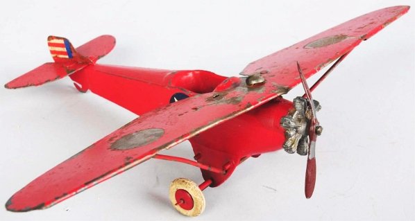 Britains Diecast Monoplane Toy.: Circa 1930s. Scarce red color variation with US markings and two star decals on fuselage. Some paint loss and wear to middle portion of wing and no decals on top or back of wing. Still displays well. 