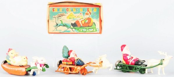 Lot of 3: Celluloid & Tin Holiday Wind-Up Toys.: Japanese. Working. Includes two Santa Claus in sled toys (one with tree in back) and one Easter Parade rabbit pulling chicks. Includes original box for one of the Santa Claus toys with some creasing o