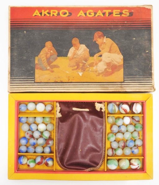Akro Agate No. 250 Marble Box Set.: Box set includes approximately 53 marbles, majority are patched oxbloods. Also includes original marble pouch. Box top has one tear and box bottom is in good condition. Condition Marbles (9.0) Box (Fa
