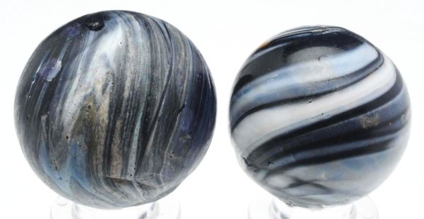 Lot of 2: Double Pontil Slag Marbles.: Both marbles have a black base, the smallest with white outer bands running from pontil to pontil and the larger marble with blue and white lines running from pontil to pontil. Several subsurface refl