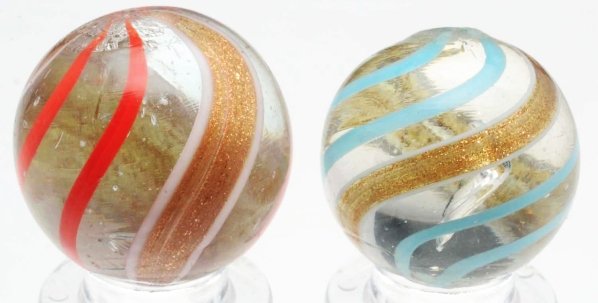 Lot of 2: Banded Lutz Marbles.: Smallest marble is a clear base with baby blue lines. The largest marble is a clear base with orange lines and wide bold Lutz banding. Condition (9.0). Size 13/16" to 7/8" Dia.