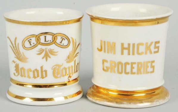Lot of 2: Shaving Mugs.: Includes one with gilt name "Jacob Taylor" and one with gilt name "Jim Hicks Groceries". Condition (Excellent). Size Each: 4" T.