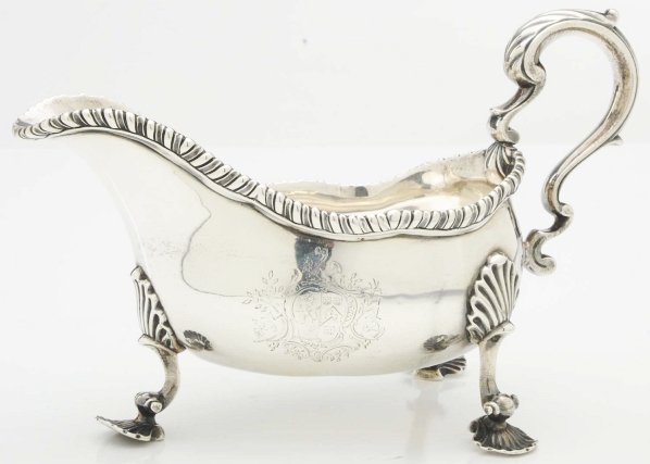 An English Silver Gravy or Sauce Boat.: Daniel Smith & Robert Sharp London 1760 Of typical form, the ovoid body with a cast gadrooned rim, double scroll handle and on three cast shell pad feet, the side engraved with a coat of arms. Minor d