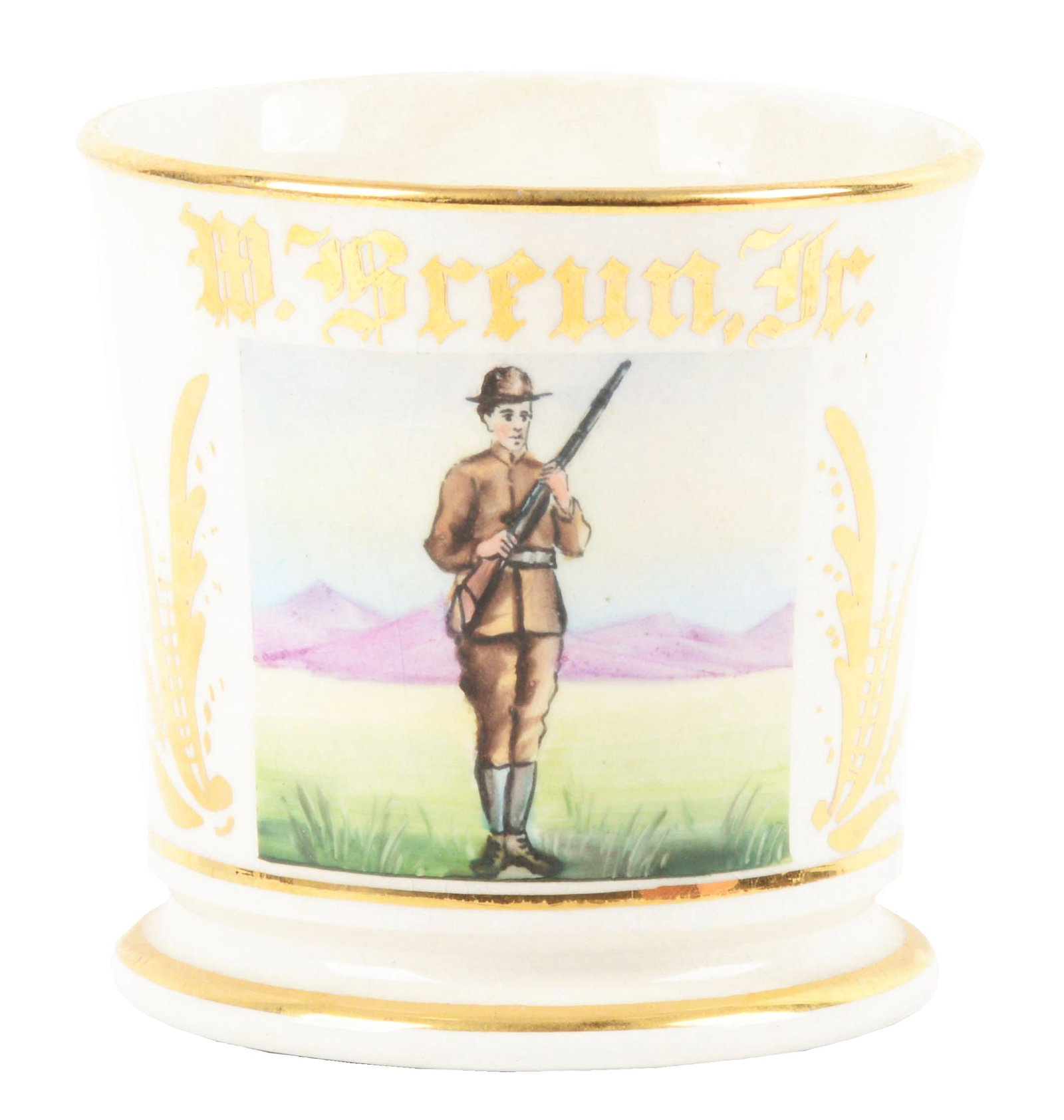 SOLDIER SHAVING MUG.: W. Breun Jr. in gold gilt. Mug is stamped "K.T. in Kay China" under base. Nice image of soldier holding rifle. Minor crazing throughout. Condition: (Excellent). Dimensions: 4 - 1/2" x 3 - 1/2" x 3 - 1