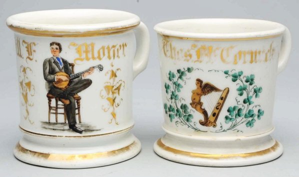 Lot of 2: Shaving Mugs.: Includes one man playing a banjo and one harp. Both with some wear to gilding. Condition (Excellent). Size Largest: 3 - 3/4" T.