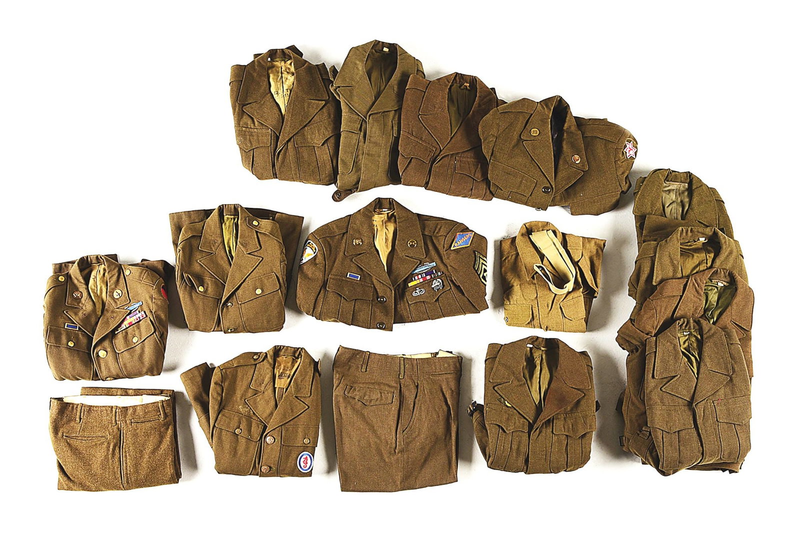 MASSIVE LOT OF US WWII ARMY UNIFORMS.: An immense lot of World War II uniforms, mostly from the US Army and comprising of wool trousers, khaki and wool shirts, and uniform jackets including Ike jackets and 4 pocket tunics. Many of the jack