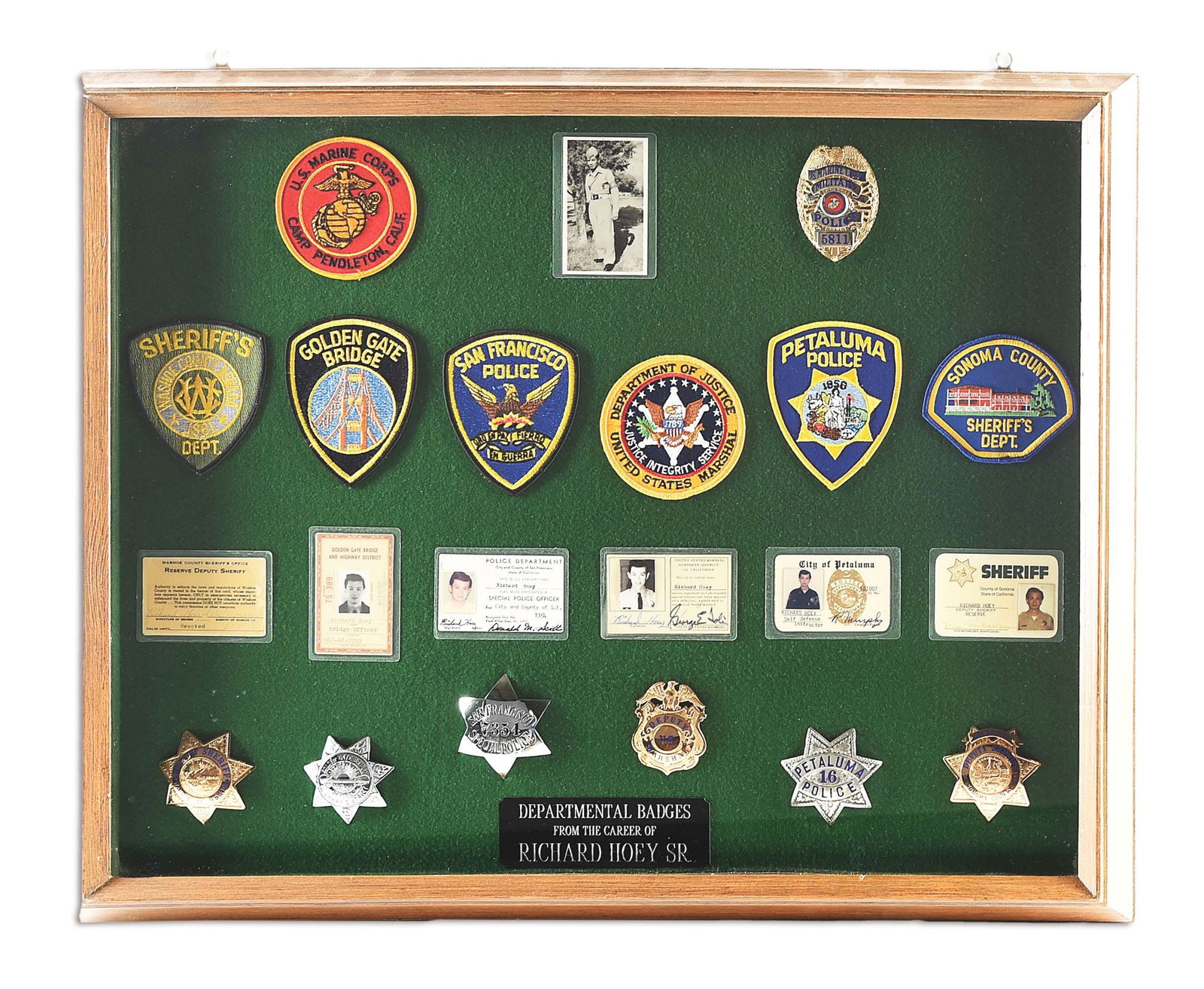 FRAMED DISPLAY OF POLICE BADGES FROM THE CAREER OF RICHARD HOEY.: Nicely framed display of desirable Bay Area, Northern California, U.S. Marshal, Deputy Sheriff, and Military Police officer official badges. Circa 1960s -1970s. Includes corresponding ID cards and dep