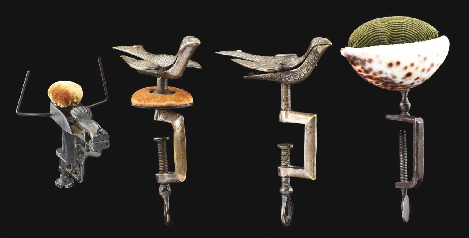LOT OF 4: ANTIQUE SEWING CLAMPS.: (A) Bird sewing clamp, dated 1853, 5" tall. (B) Bird sewing clamp, embossed body with pincushion, 5" tall. (C) Seashell clamp with pincushion top, 5" tall. (D) Early steel clamp with pincushion, 3 - 1