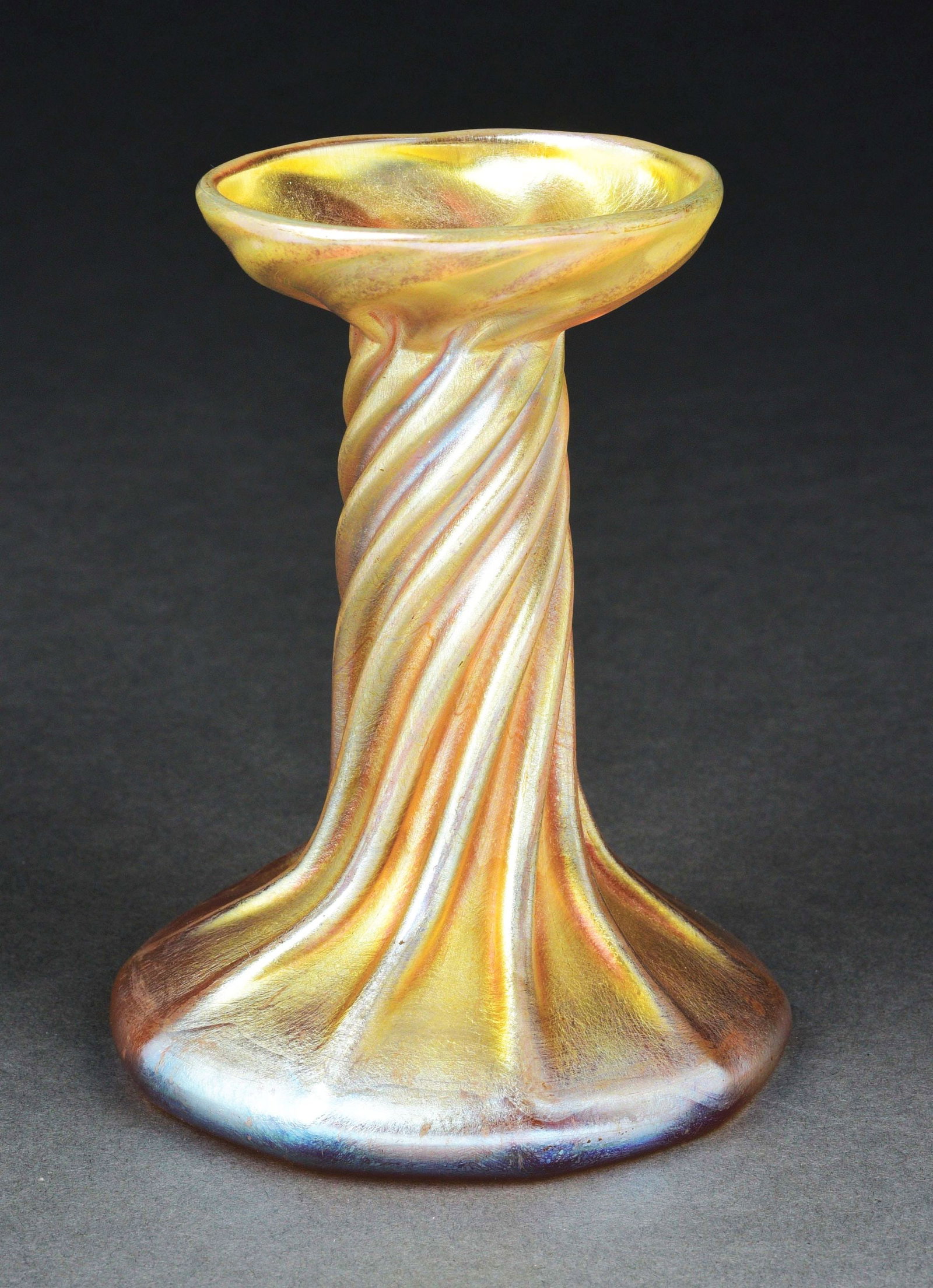 TIFFANY STUDIOS FAVRILE GLASS CANDLESTICK.: Lovely Favrile glass candlestick by Tiffany Studios. Stands 5” tall, composed of iridescent gold Favrile glass in a twisted ribbed form. The underside is signed “LCT.” CONDITION: Exc