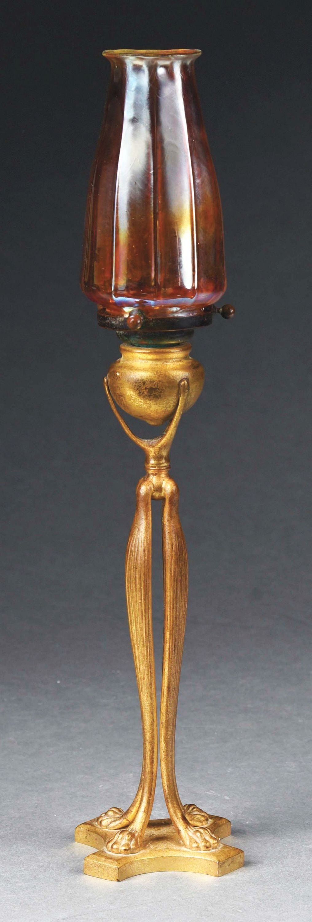 TIFFANY STUDIOS CANDLESTICK WITH TULIP SHADE: A beautiful candlestick lamp by Tiffany Studios. The Favrile glass tulip shade is gold with prominent iridescent tones of pink and blue. There is strong ribbing. The shade is signed "LCT" to the fitte